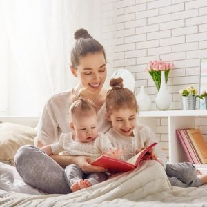 Young mother reading a book to her children.