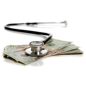 A stethoscope and American money on a white background.